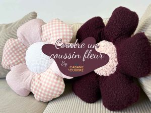 Coudre un coussin fleur : deux coussins décoratifs en forme de fleur, un modèle en tissu rose vichy et un modèle en bouclette prune – tutoriel vidéo gratuit La Cabane à Coudre sur YouTube.