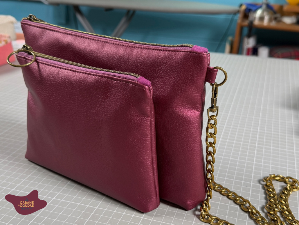 Sac 3-en-1 Léna en simili cuir rose métallisé, avec ses deux trousses zippées et sa bandoulière chaîne dorée.